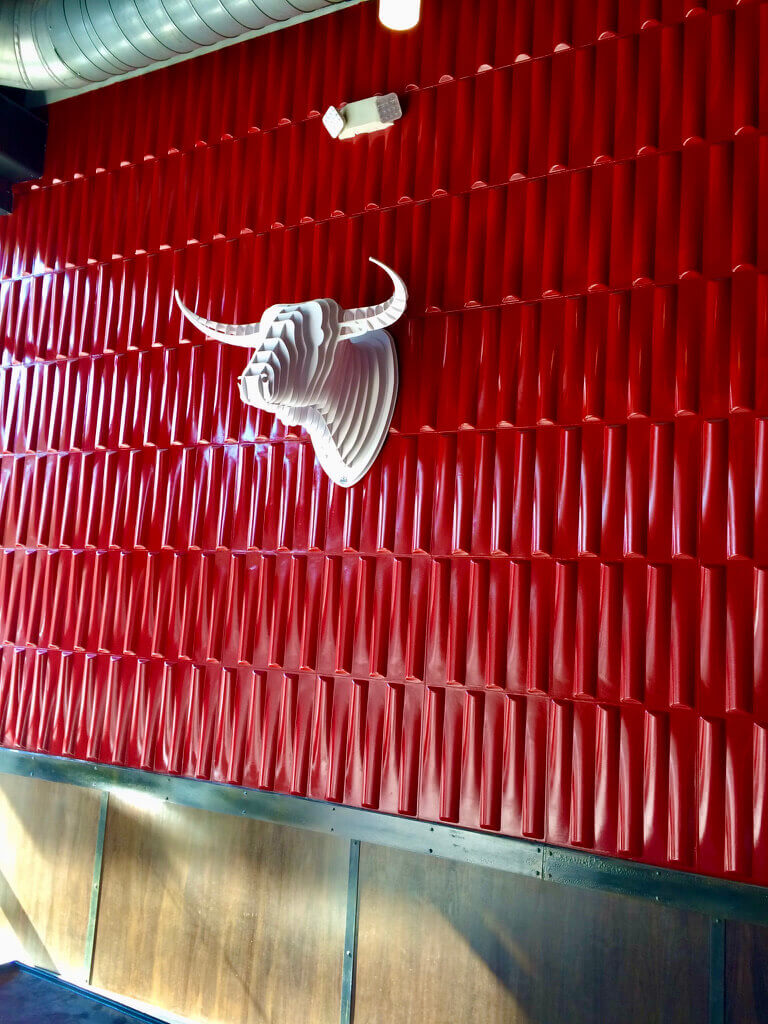 Red wall art with white fake longhorn head on the wall at Salvation Pizza in Domain Northside in Austin, Texas