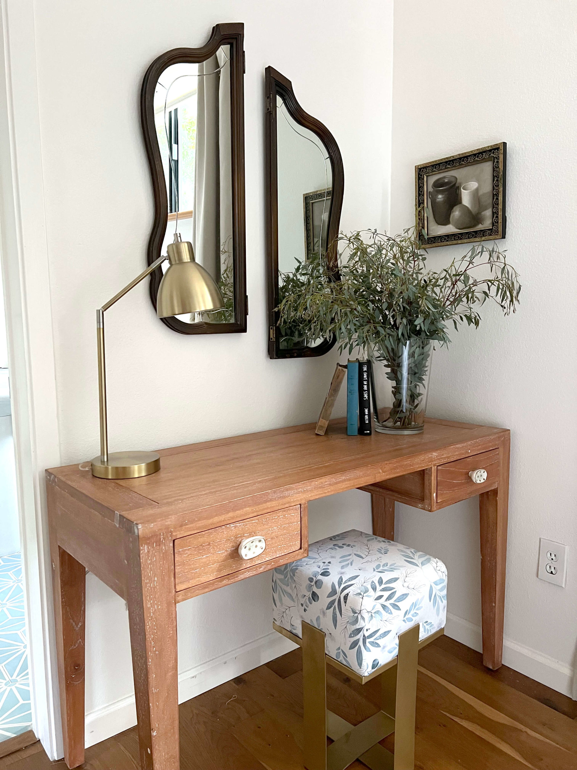 Vanity table with stool, lamp, books, green florals, and mirrors from Uncommon Objects in bedroom in Bouldin Creek Airbnb in South Austin, Texas