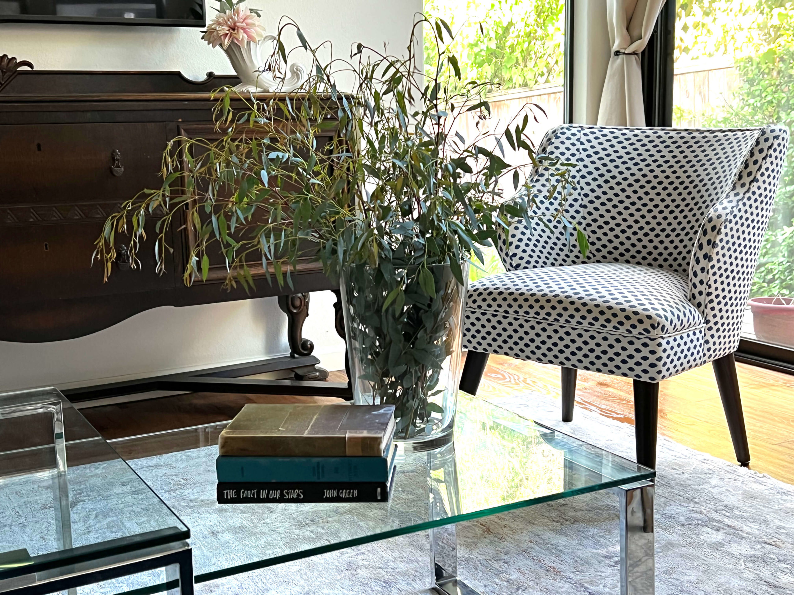 Coffee table in Bouldin Creek Airbnb in South Austin, Texas with books and green floral arrangement with chair in background