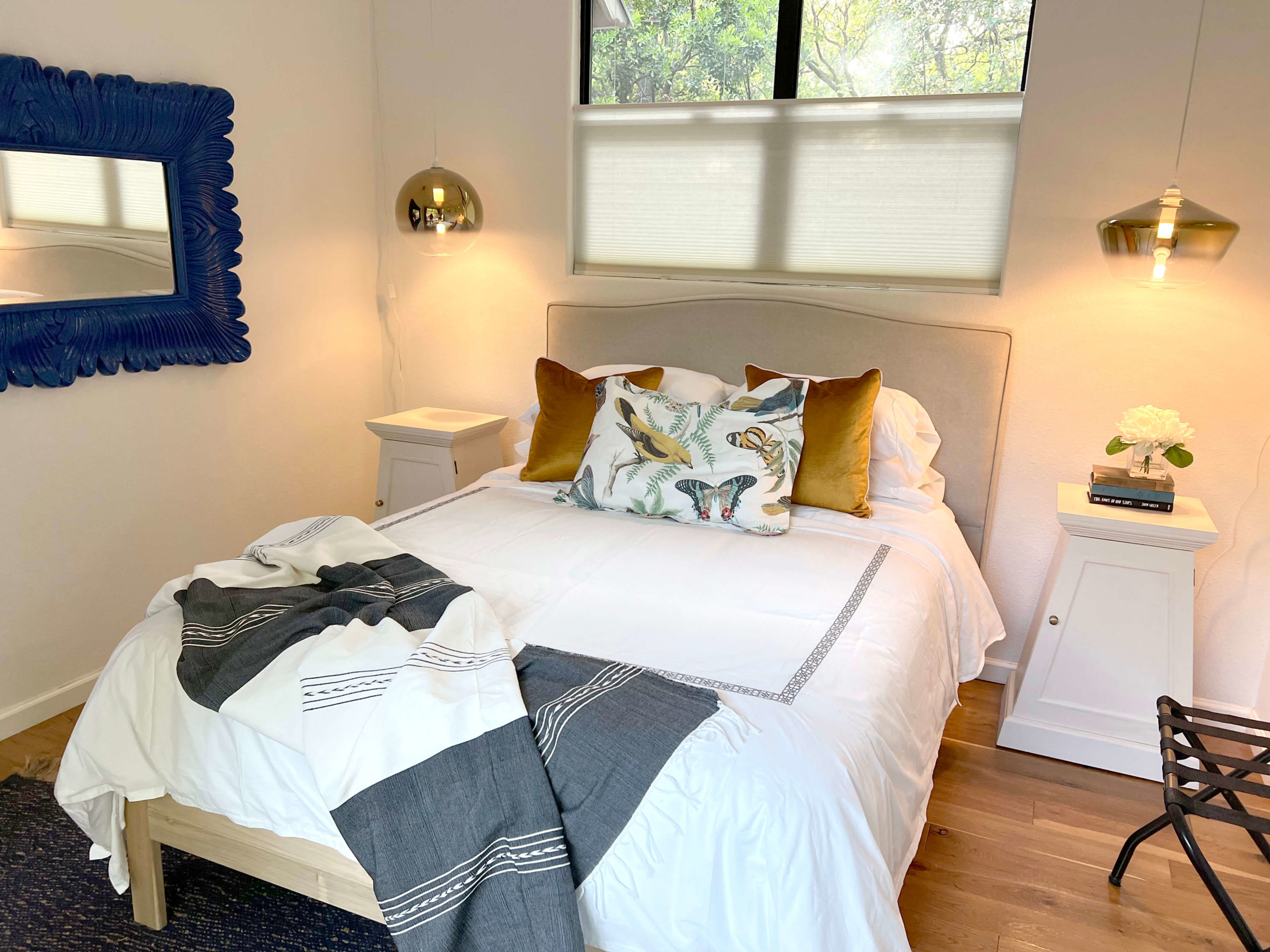 Main bedroom of Bouldin Creek Airbnb in South Austin, Texas, with Mexican bedspread, butterfly pillow, yellow pillows, hanging pendant lights